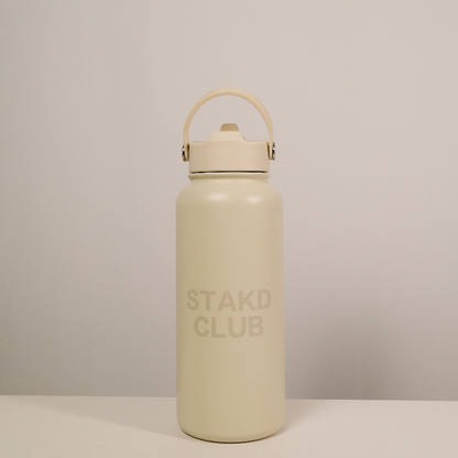Beige water bottle with 'STAKD CLUB' branding on a light gray background