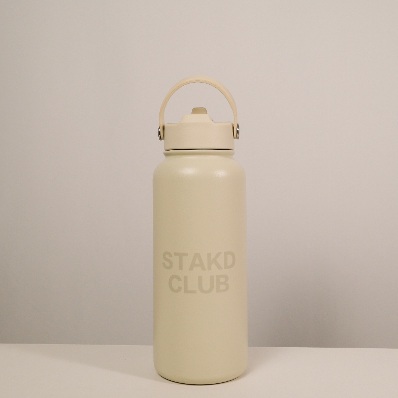 Beige water bottle with 'STAKD CLUB' branding on a light gray background