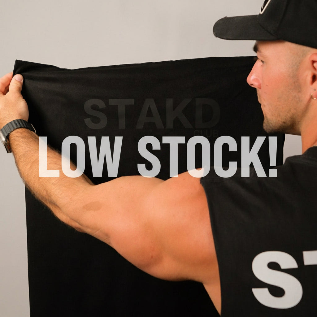 Person holding a black STAKD branded sheet against a plain background
