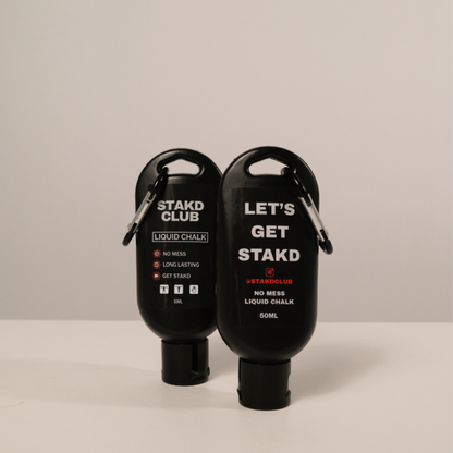 Two black liquid chalk bottles with carabiners on a beige background
